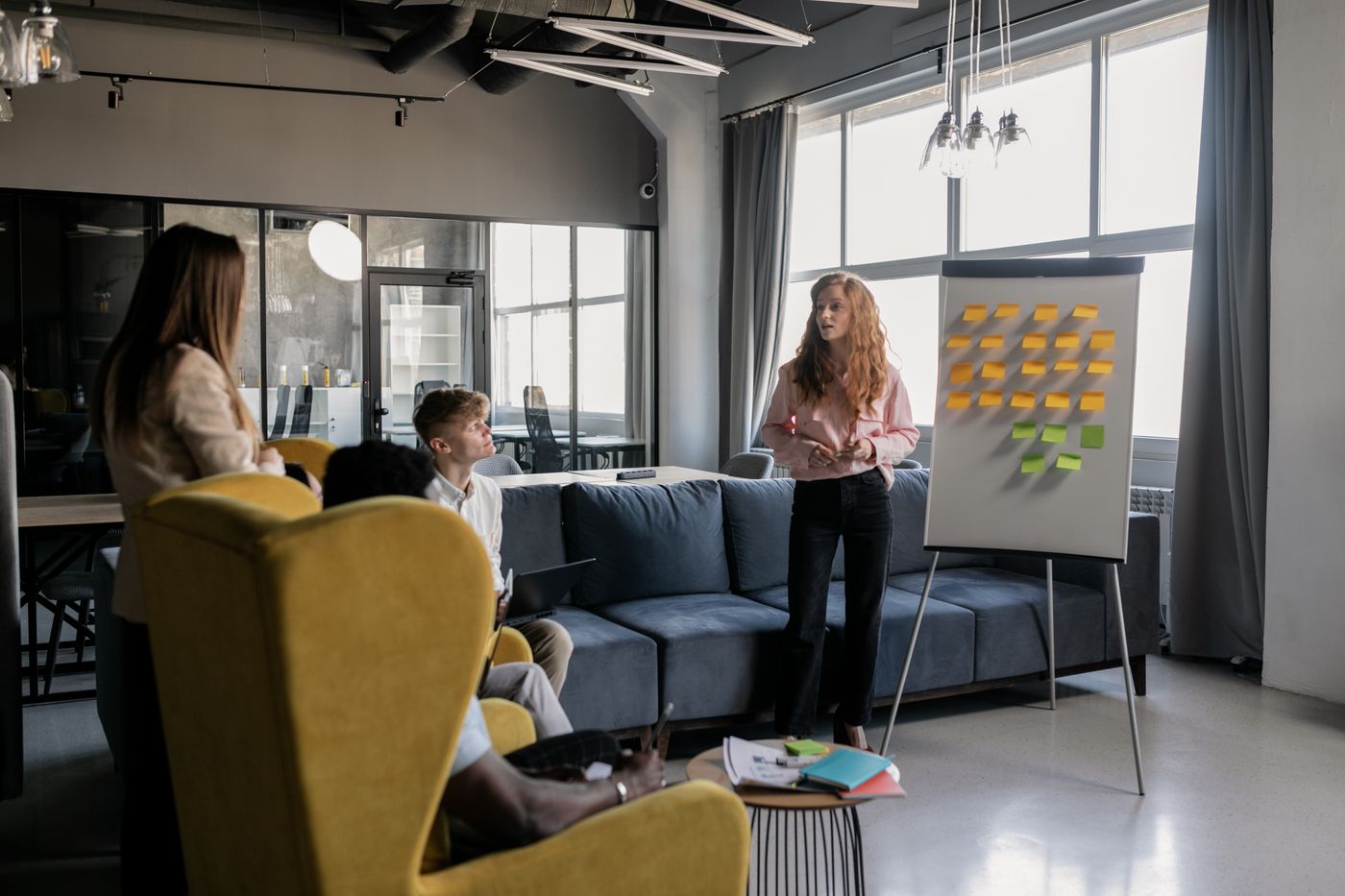 Una responsabile spiega ai colleghi le procedure di lavoro su una lavagna con i post-it